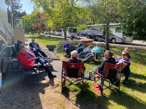 Group of people gathered in lawn chairs sitting outside a motorhome.